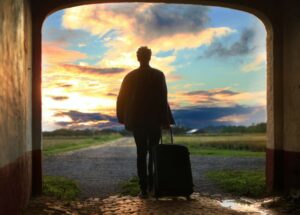 man with traveling suitcase looking out at a beautiful countryside with a desire to travel