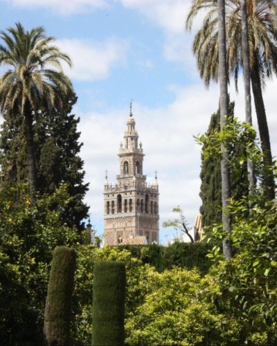 A captivating scene where traditional Moorish architecture, with its intricate designs, meets the lush, untamed beauty of nature in Seville, Spain